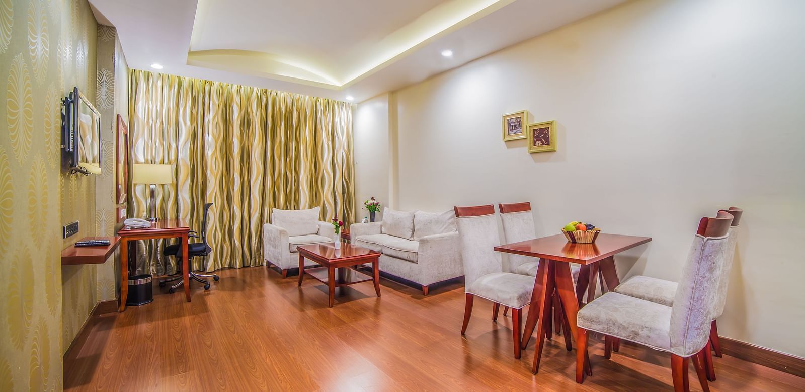 A bright and inviting hotel dining area with a wooden table set for two A grand hotel suite with an opulent red and white decor, large bed, and seating area, reflecting a traditional style at Sitara Luxury Hotel in Hyderabad near Ramoji Film City.