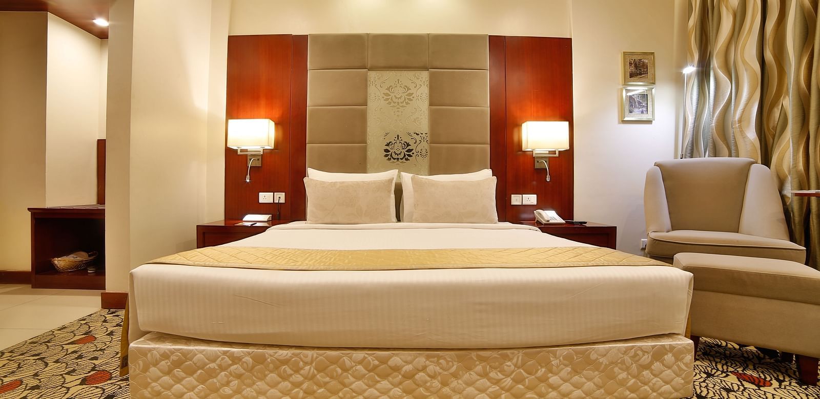 A sophisticated hotel bedroom with a large comfortable bed, modern amenities, and soft lighting A grand hotel suite with an opulent red and white decor, large bed, and seating area, reflecting a traditional style at Sitara Luxury Hotel in Hyderabad near Ra