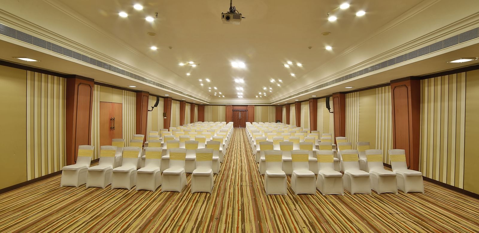  Seating arrangement in Terrace Hall A grand hotel suite with an opulent red and white decor, large bed, and seating area, reflecting a traditional style at Sitara Luxury Hotel in Hyderabad near Ramoji Film City.