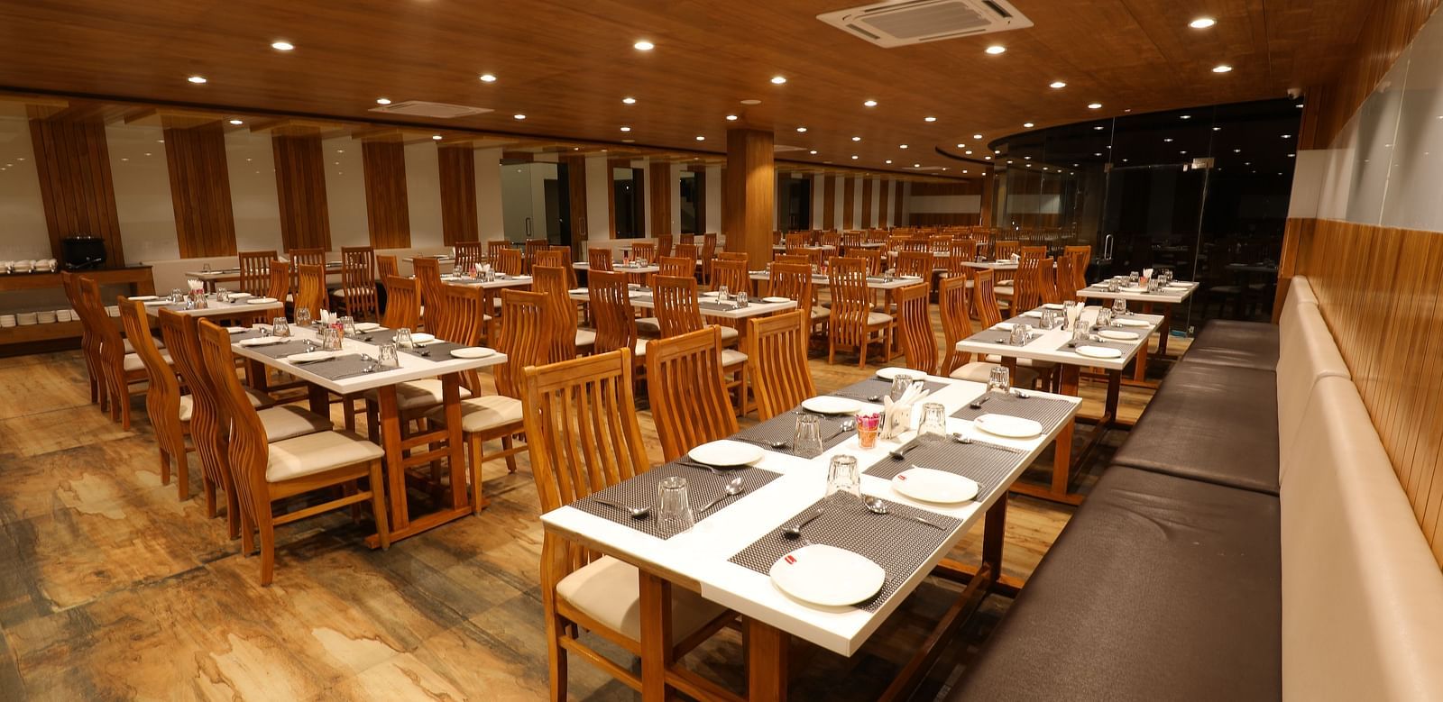 Warmly lit interiors of the Blue Coriander Restaurant with wooden tables and chairs in a cosy atmosphere - Vishal Lords Inn Gir Forest