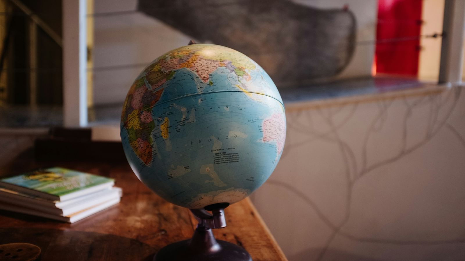 a globe kept on a table with books behind it