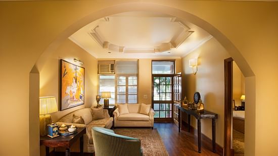 An image of a living room features comfy sofas, large windows, wall paintings, and other decorative items - Lamrin Boutique Cottages Rishikesh