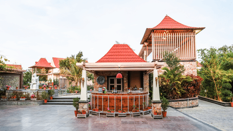 An outdoor courtyard at Estherea Resort & Spa, Jaipur, featuring a circular wooden bar with a red roof and stone flooring.