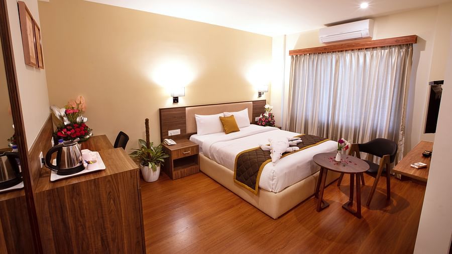 Wooden workstation with a tea/coffee setup, wall art, and a comfortable chair - RK Gardenia, Surya City.