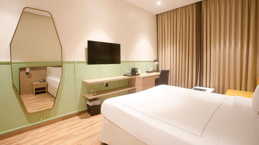 A corner view of the Superior Deluxe room at Hotel Bawa Regency, Dadar, focusing on the mirror and flat-screen TV.
