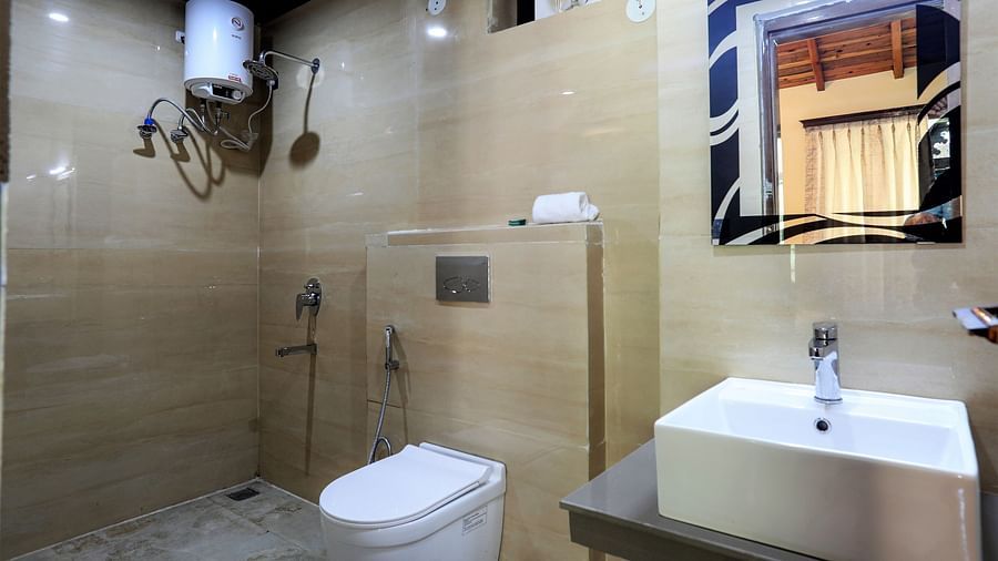 A bathroom with a sink, a square mirror, a geyser, a western toilet and a shower space - Vinsober Monal, Nainital