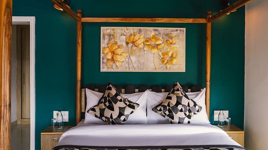 A neatly made bed with a photo frame above the headboard, a bedside table on each side, and a wooden frame at BluSalzz Villas - The Green Roof, Bhimtal.