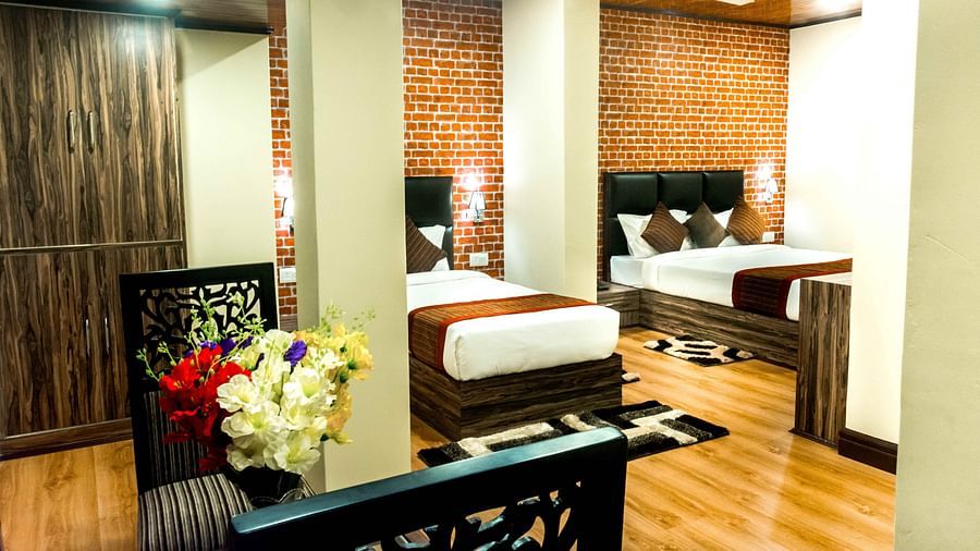An image of the suite with twin beds, bed side tables, chair, ceiling and other amenities in a room which is brightly lit - Ecotel Tin Tin, Bijanbari