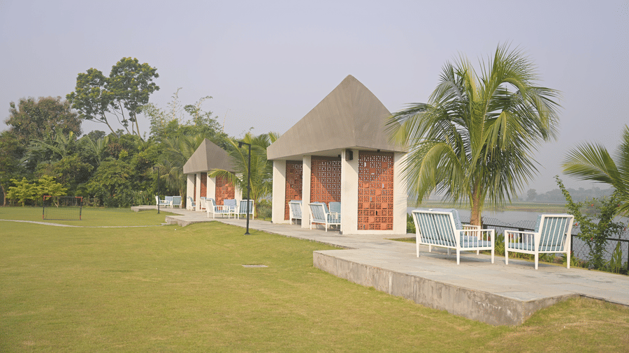 Small gazebo-style structure surrounded by open lawns and palm trees at Hotel Sonar Bangla Mayapur.