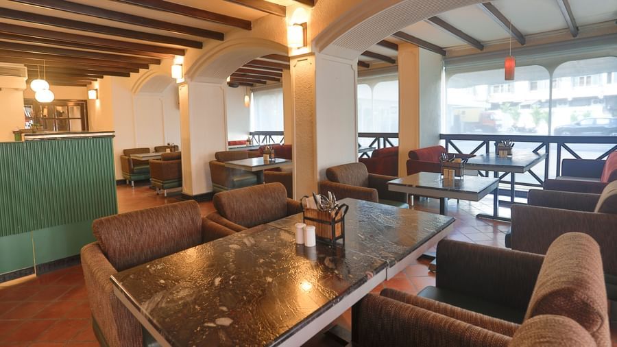 An inviting restaurant interior at Shilton International, Kochi, features a mix of dining tables and lounge seating, with a bar area.