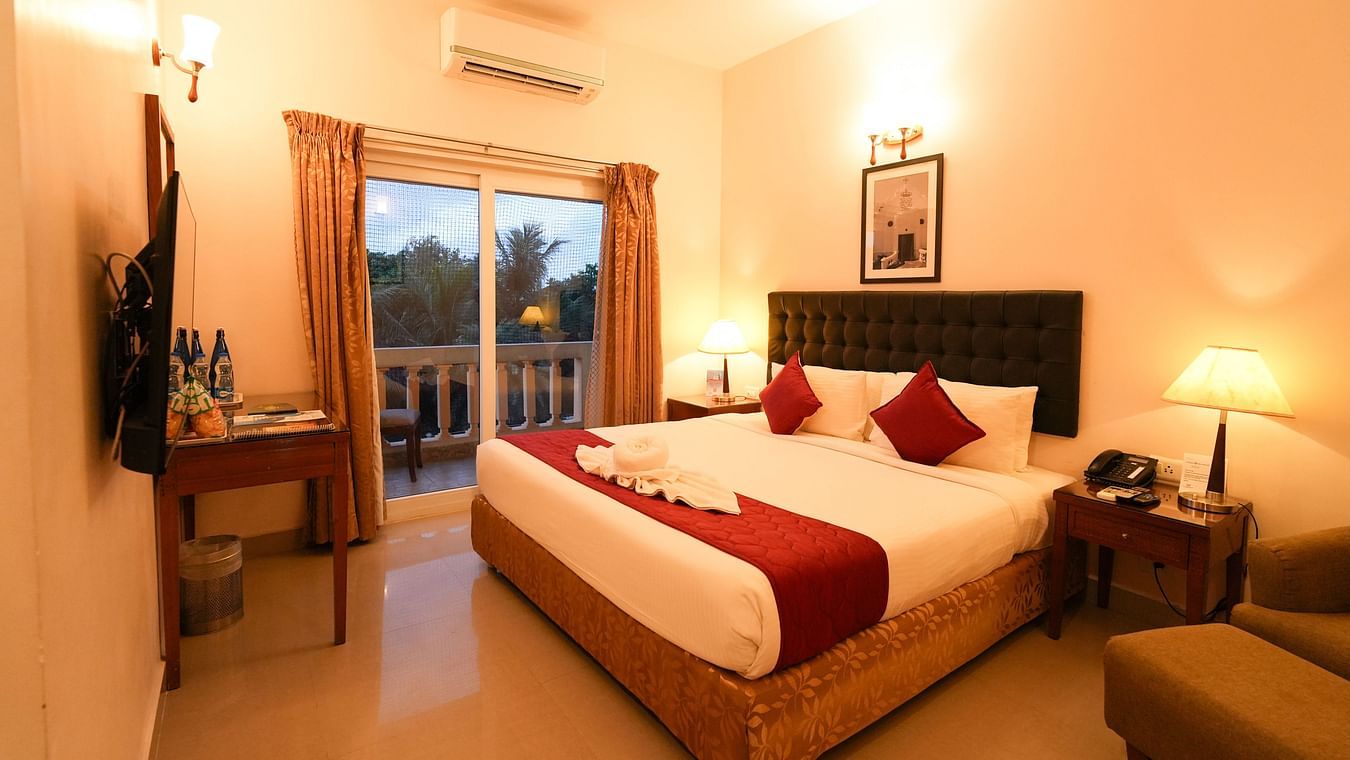 Image of Grandeur Pool View Suite featuring a plush bed facing the TV on the wall and the door to balcony next to the nightstand