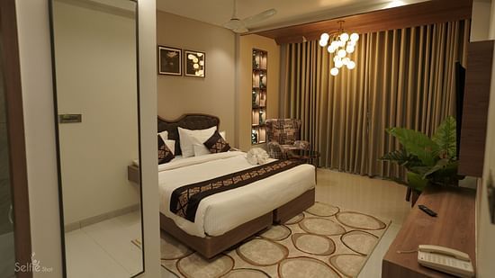 Suite Room at Pride Comfort, Dwarka with a double bed, a television and a chandelier