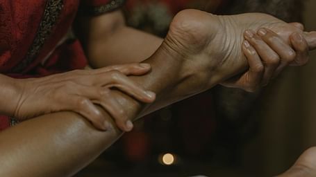 A therapist holding a person's toe with one hand while providing a massage with the other hand.