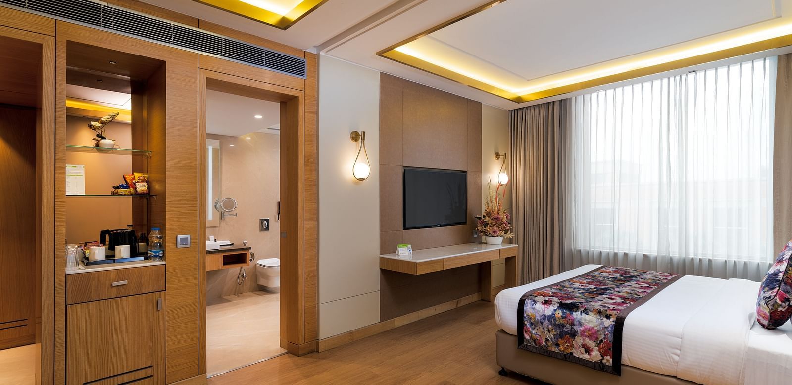 A room with a double bed placed in front of a TV at Nirvana Luxury Hotel, Ludhiana.