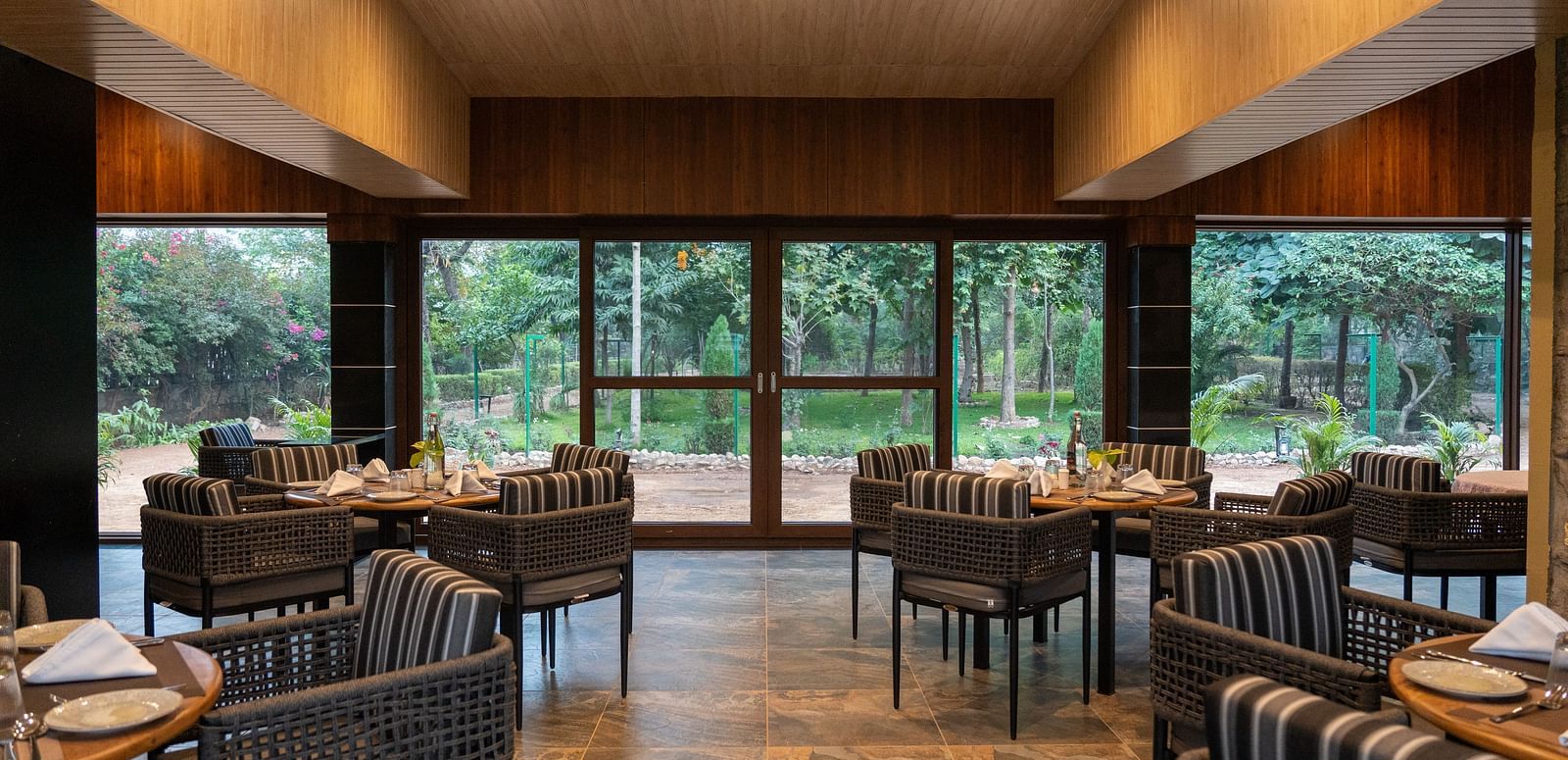 A comfortable dining space at Aamaghati Jungle Retreat Ranthambore with modern furniture and an outdoor view.