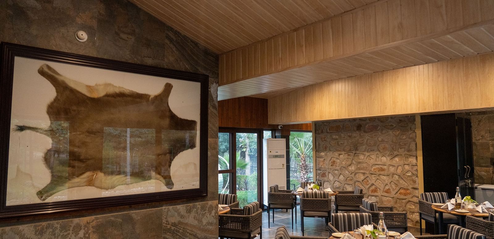 A spacious dining area at Aamaghati Jungle Retreat Ranthambore with stone walls and unique animal hide decor.