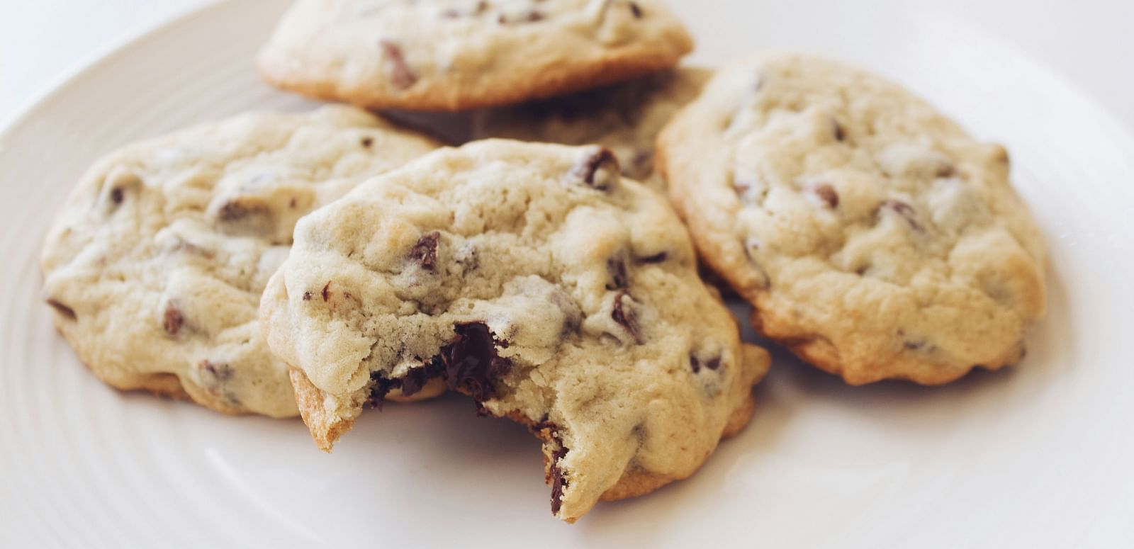 A few chocolate chip cookies placed on a white plate.