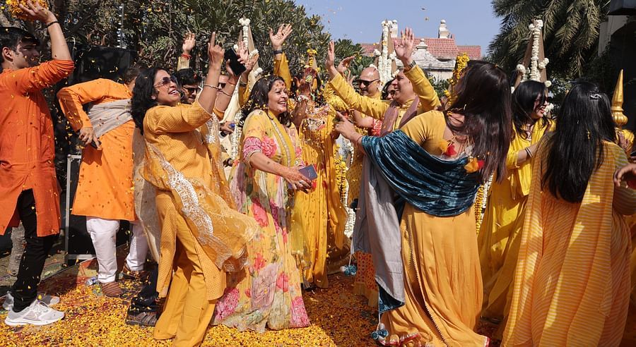 alt-text Family and friends dancing and celebrating amidst marigold decorations during a wedding ceremony at Shri Radha Brij Vasundhara Resort & Spa.