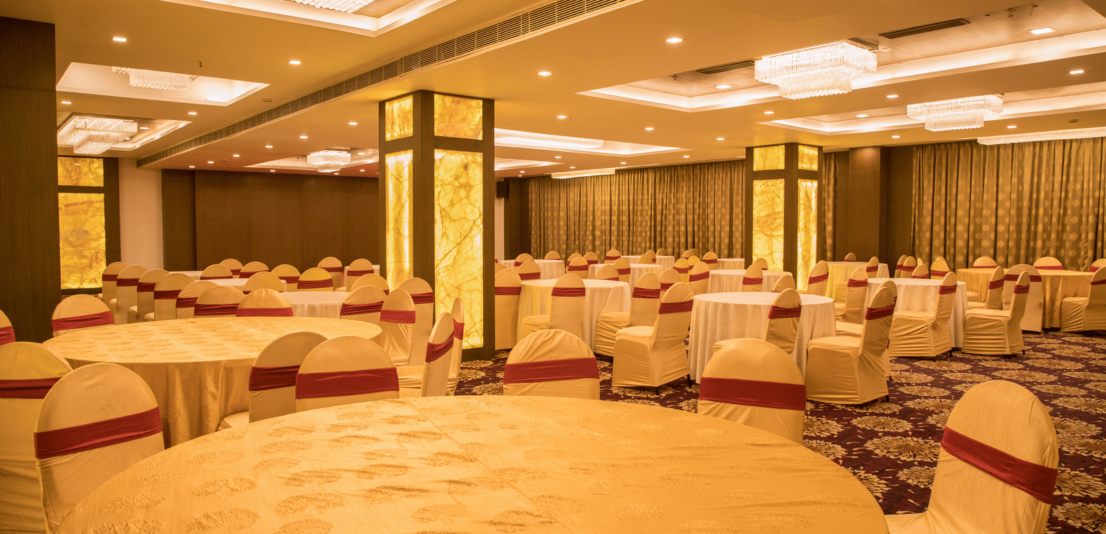 A large banquet hall at Benzz Park Chennai with multiple round tables and chairs, ready for a function.