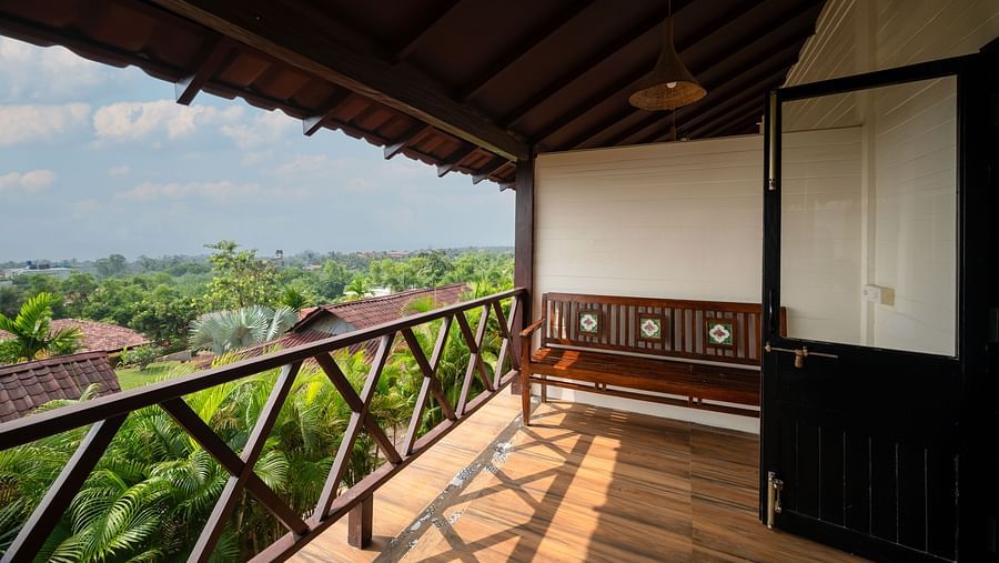 An image of a balcony with a lush view, shot from a corridor, and a fan in the shot.