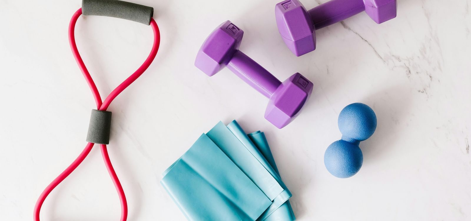 A resistance band, dumbbells and a skipping rope placed on the floor.