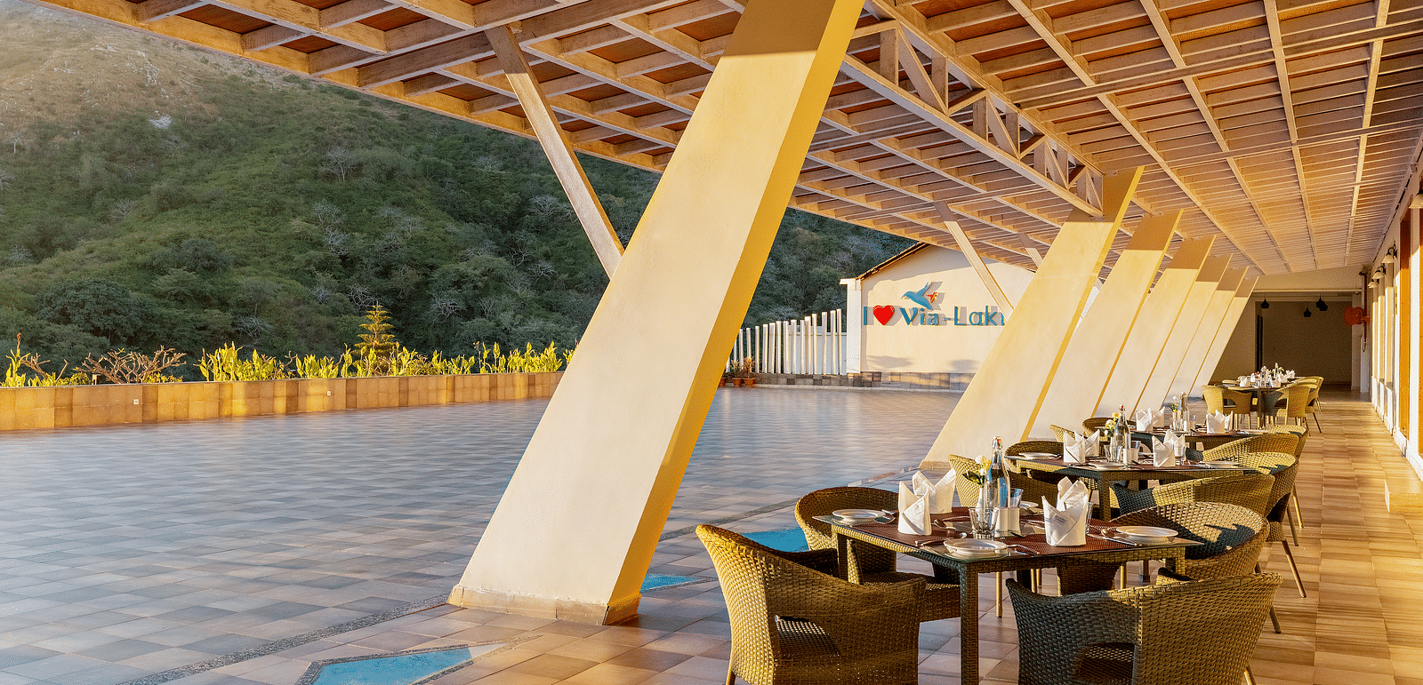 Outdoor dining area with tables, chairs, and a unique sloped roof - Via Lakhela Resort & Spa