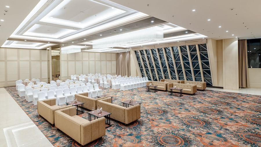 A wide angle shot of a banquet hall in ajmer featuring cosy seating arrangement, high ceilings, and bright lighting - Sarovar Portico, Ajmer