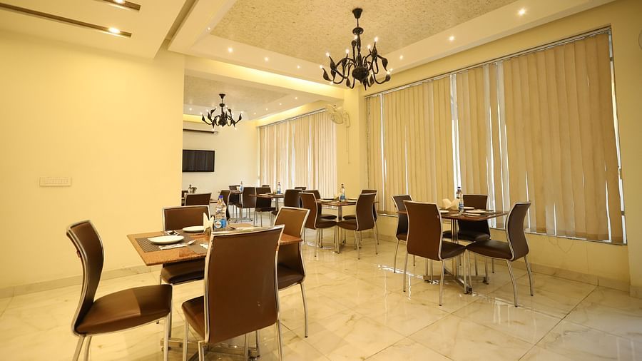 A brightly lit dining area features multiple tables and chairs - Asian Suites Cyber Park, Gurgaon