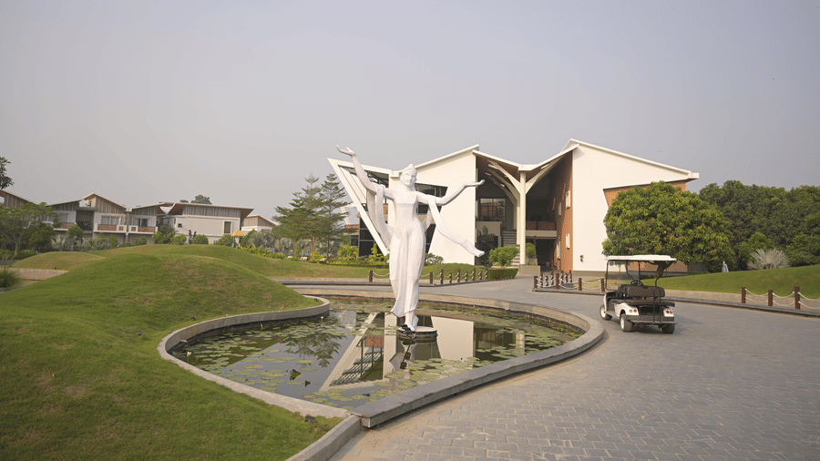 Front entrance of Hotel Sonar Bangla, Mayapur, with a decorative water feature and a sculpture in the foreground.