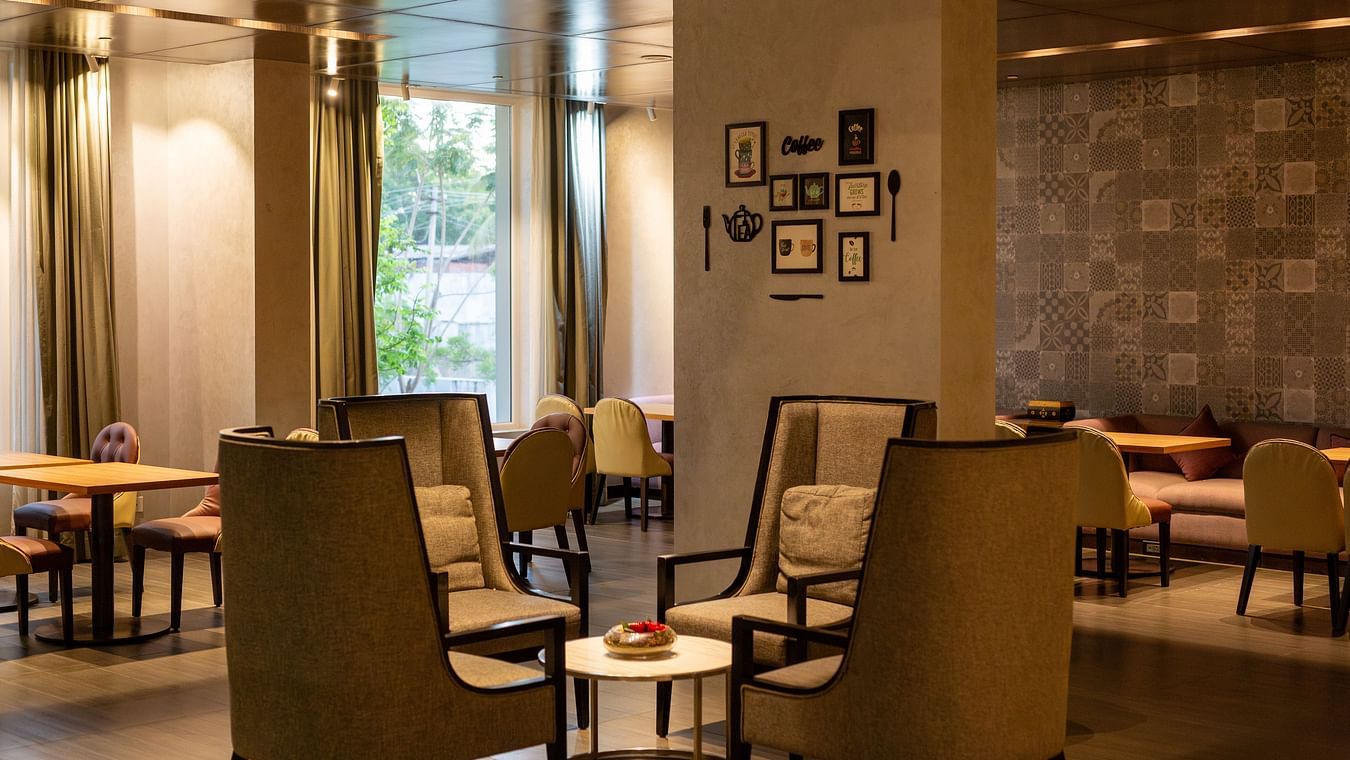 A close view of the modern restaurant interior with tables, chairs, and large windows entirely the vintage feel and look at THE RESIDENCY TOWERS RAMESWARAM