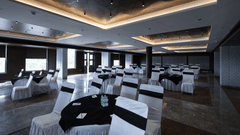 A well-lit banquet hall at Pride Resort, Jodhpur, with tables and chairs dressed in white covers and black tablecloths.