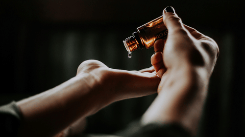 A woman pouring essential oils on her hands.