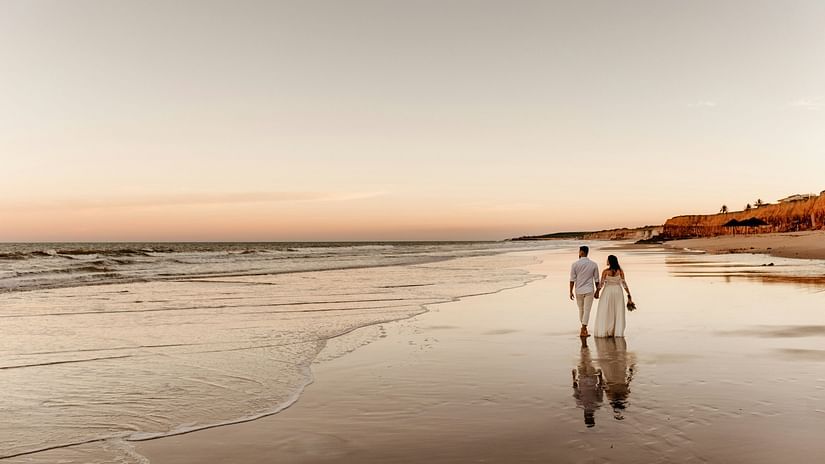 a couple walking on the beach with waves overlapping on the beach