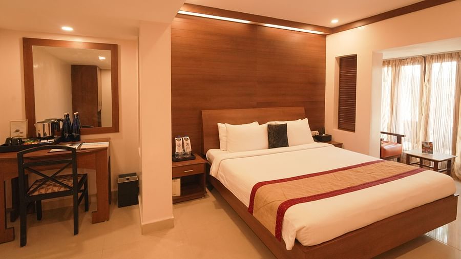 A room with a neatly arranged bed with good lighting and a desk and chair arranged in the side.