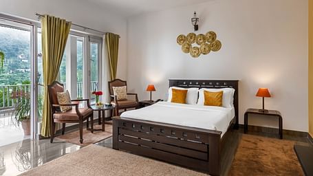 Spacious bedroom with large bed, seating area, and balcony access, at BluSalzz Collection - Suvaasa Resort, Ramgarh.