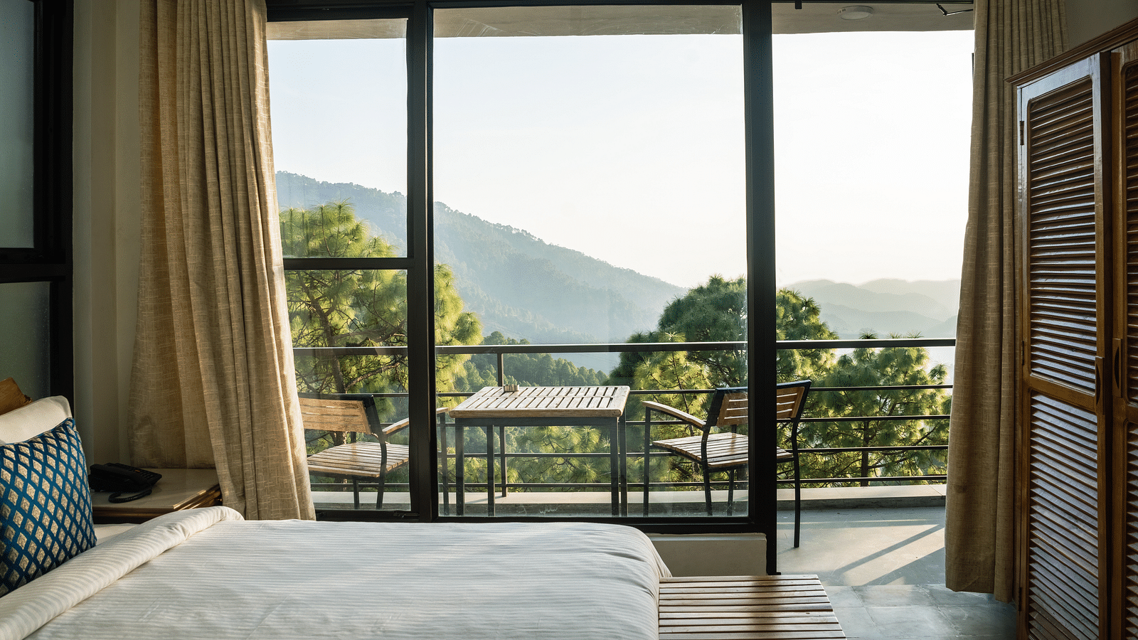 A bedroom with a balcony offering natural light and scenic views at BluSalzz Escapade Resort, Lansdowne