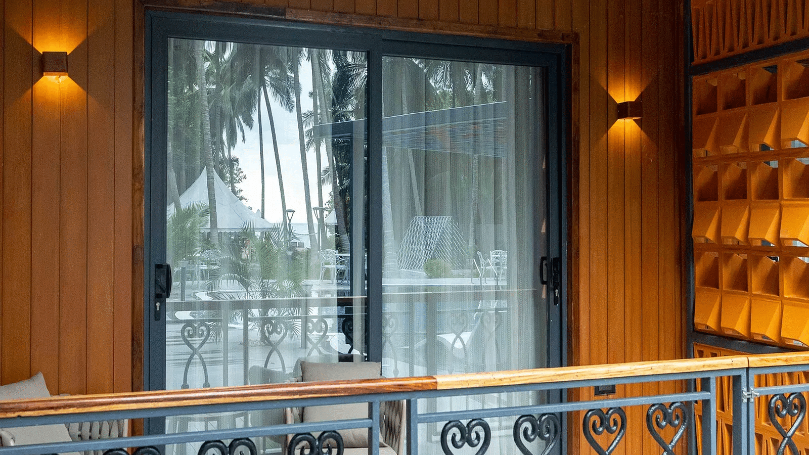 Image of Coral Sapphire at Coral Reef Resort and Spa in Havelock featuring the glass door to outdoor seating area on the balcony with the reflection of the swimming pool and trees on the glass
