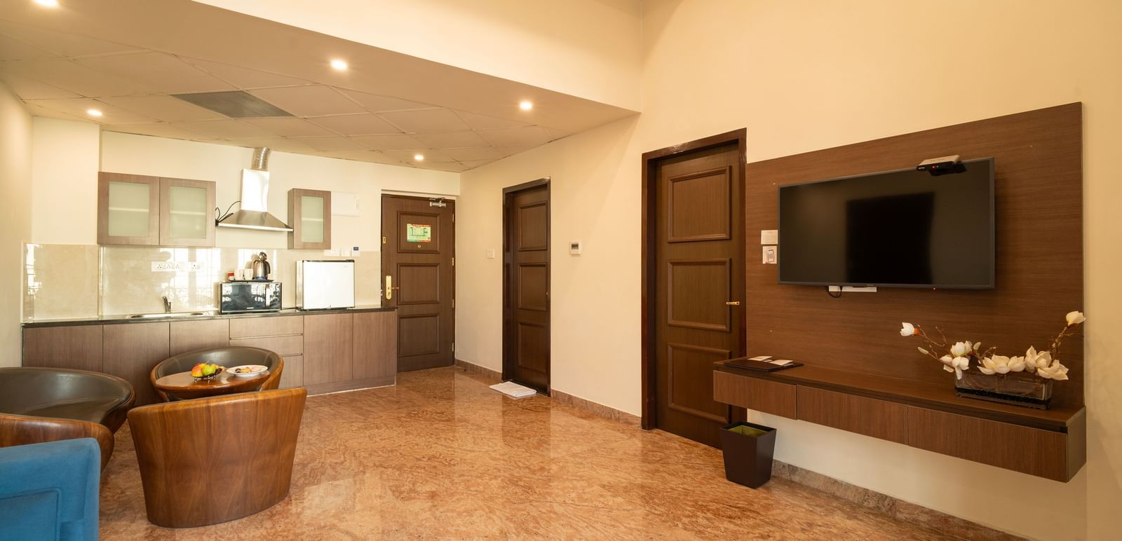 a living area in our hotel room near chennai airport featuring lounge seating, flat-screen TV, and marble flooring under soft recessed lights - Accord Chrome Airport Hotel