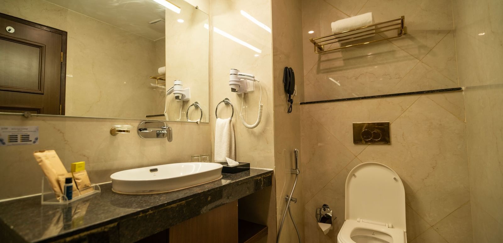 Well-lit modern bathroom with large mirror, vanity counter, and a commode - Accord Chrome Airport Hotel