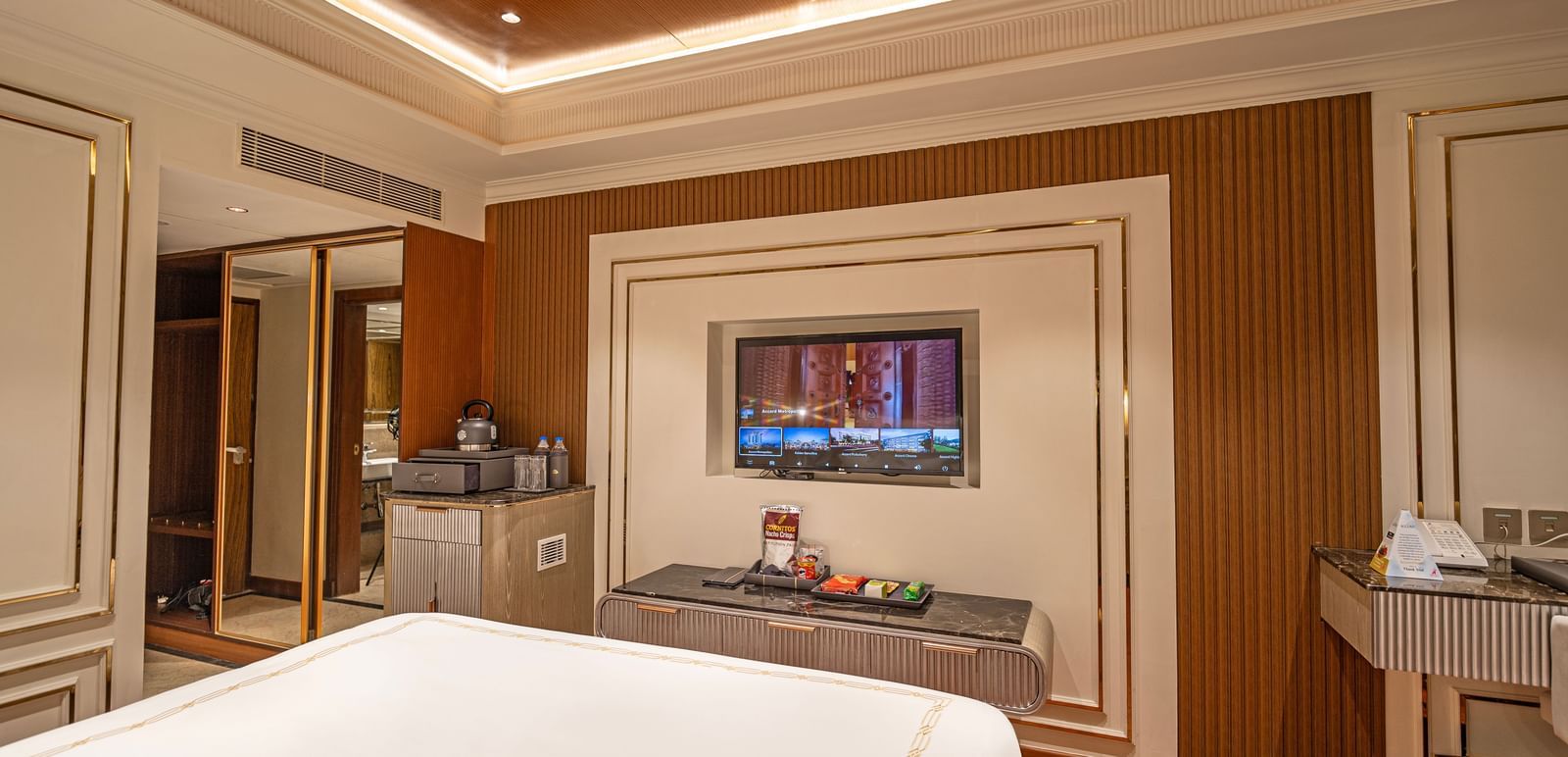 Room at Accord Metropolitan with bed, TV, desk, and ceiling lights.