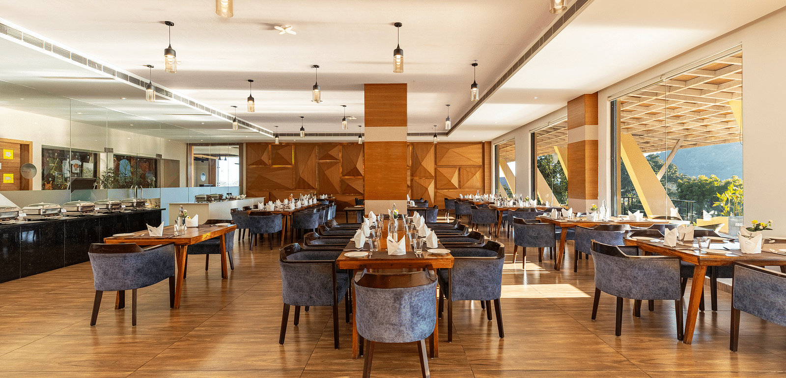 Restaurant interior with tables, chairs, and large windows under a warm lighting - 