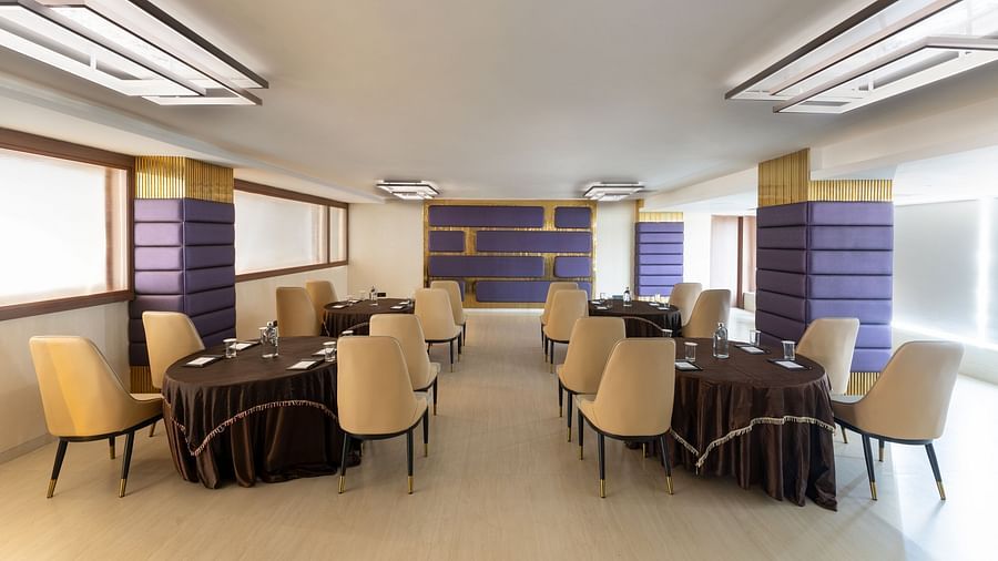 Private meeting space with round tables and beige chairs, purple-accented walls at Clarks Inn Suites, Hyderabad