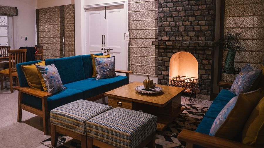 A living area with furniture arranged around a table by the fireplace at BluSalzz Villas - The Green Roof, Bhimtal.