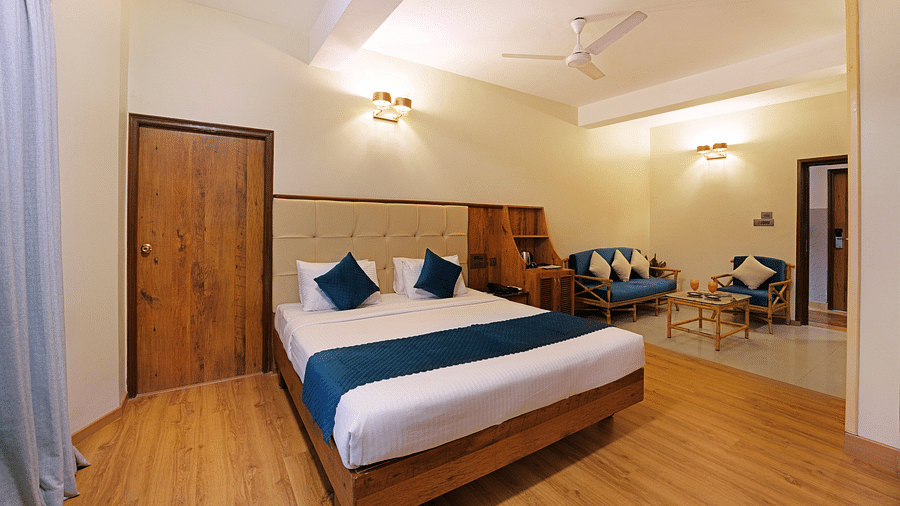 An Executive Room with a queen size bed, a couch, and a wooden decor - Cross Roads Inn, Bengaluru