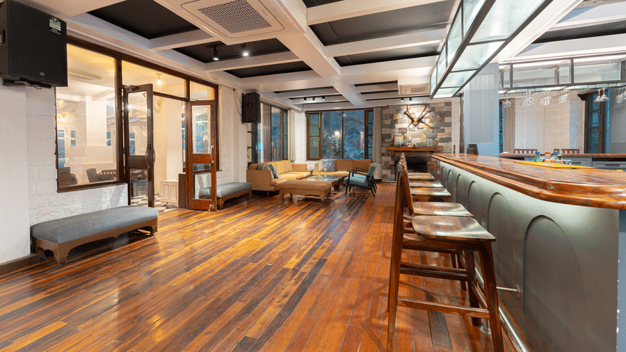 Wide-angle view of the hotel bar and social area with comfortable yellow sofas and warm lighting - Johnson Lodge & Spa, Manali