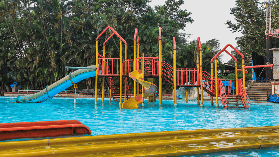 Playground-style water slide complex featuring several slides, tunnels, and multiple levels surrounded by trees at Kumar Resort by Turtle.