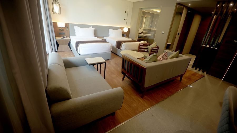 Wide-angle view of a suite with dual sofas, twin beds, and warm lighting, designed with modern wooden accents at Wyndham Garden.