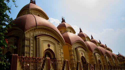a facade view of the famous Dakshineswar Kali Temple with pagoda shaped roofs captured during the day.