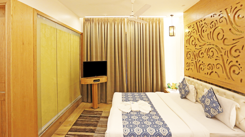 A modern hotel room featuring a spacious bed, a TV, wooden panelling, and warm lighting at JRD Luxury - Business Hotel.