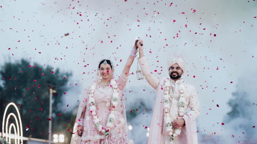 Bride and groom celebrating with confetti during a wedding ceremony at Umaid Palace.